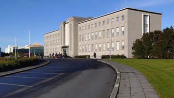 En stor grå byggnad som ligger vid sidan av en väg. Islands universitet.