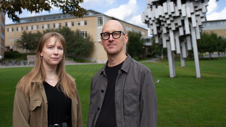 En man och en kvinna som står framför ett konstverk och en byggnad.