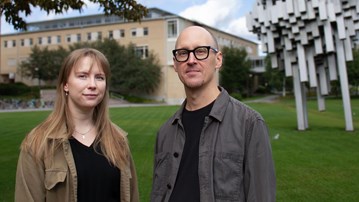 En man och en kvinna som står framför ett konstverk och en byggnad.