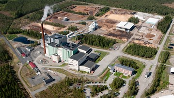 Flygfoto över kraftvärmeverk omgivet av skog.