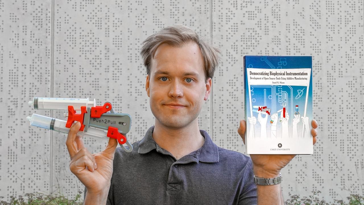 En man som håller upp en bok och ett forskningsinstrument.