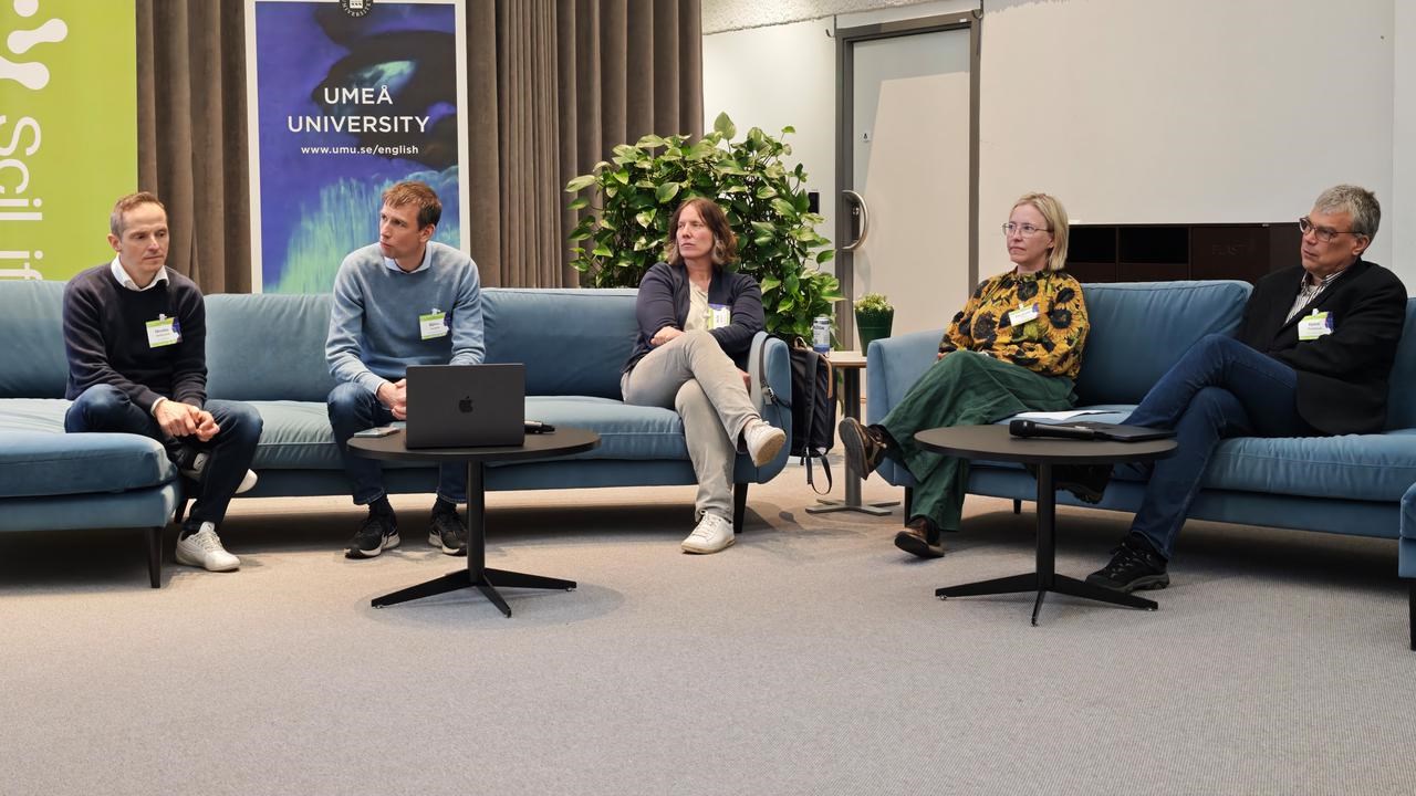 A group of people sitting on couches in a room during the panel discussion at the scientific conference