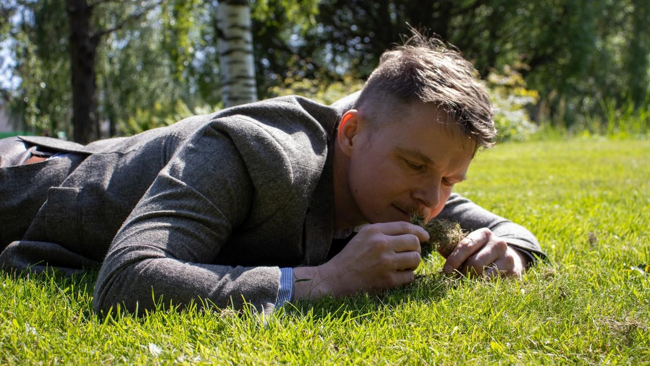 En man som ligger i gräset och luktar på nyklippt gräs.