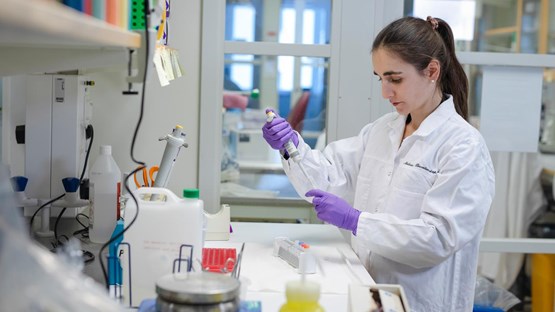 Doktoranden Laura Leykam står vid sin labbänk och pipetterar upp lösligt prov ur ett mikrocentrifugrör.