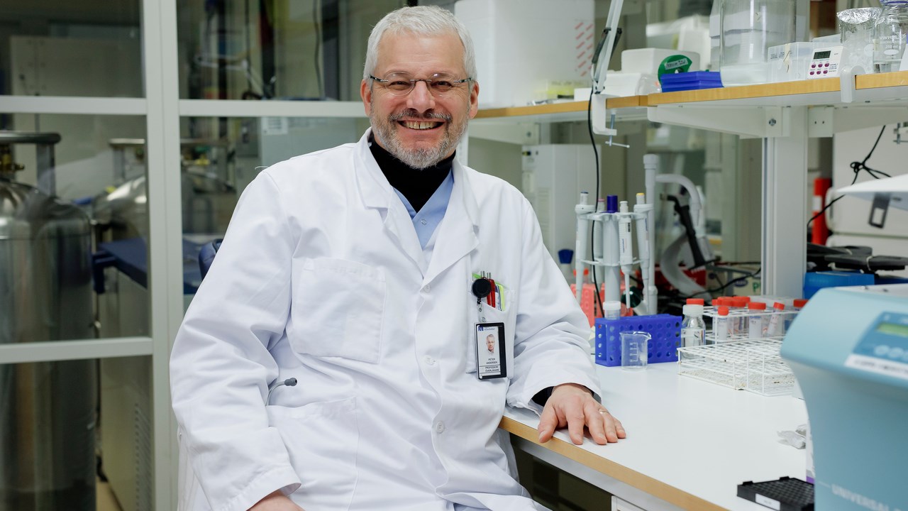 Principal investigator Peter Andersen sitting at a lab bench in his laboratory smiling.