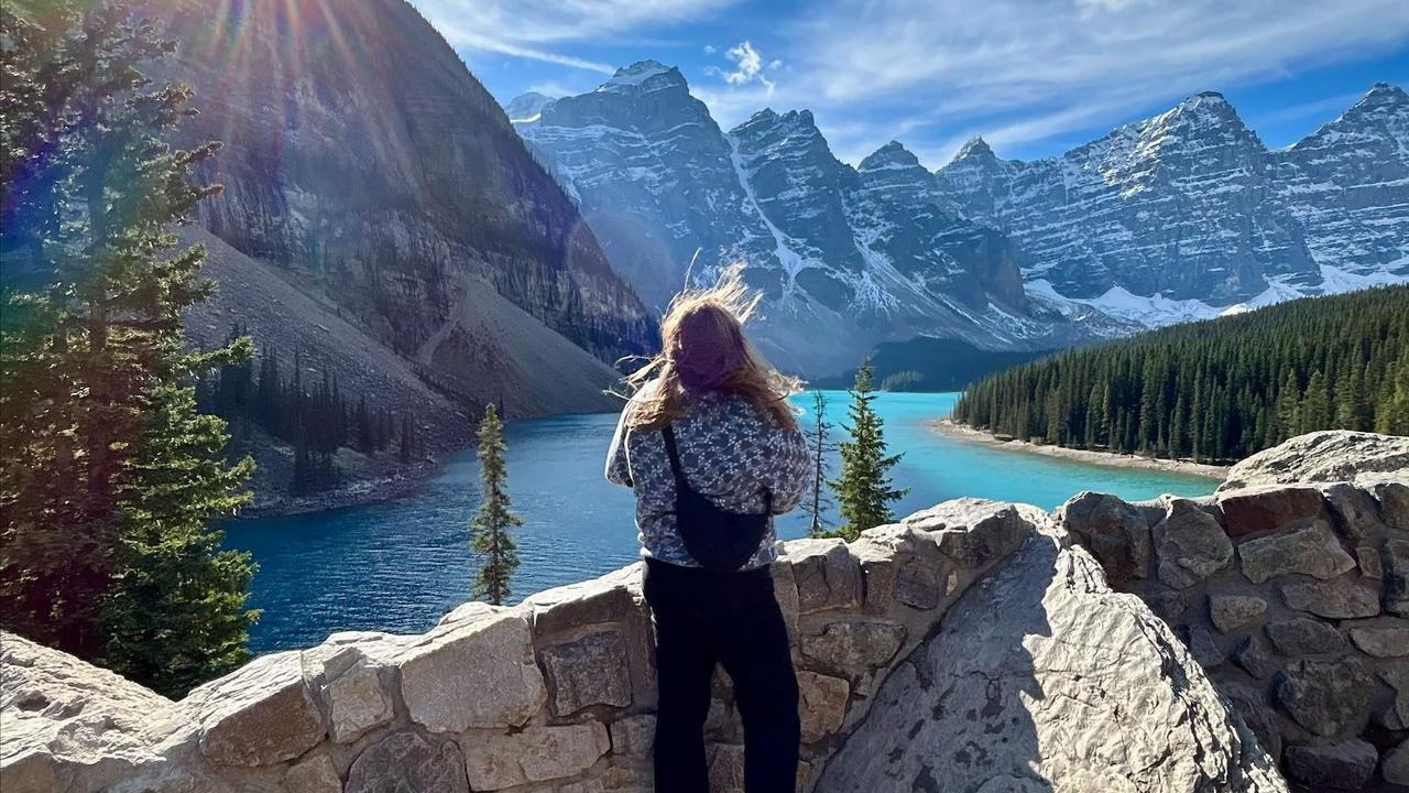 En kvinna står på en klippvägg med utsikt över en sjö.