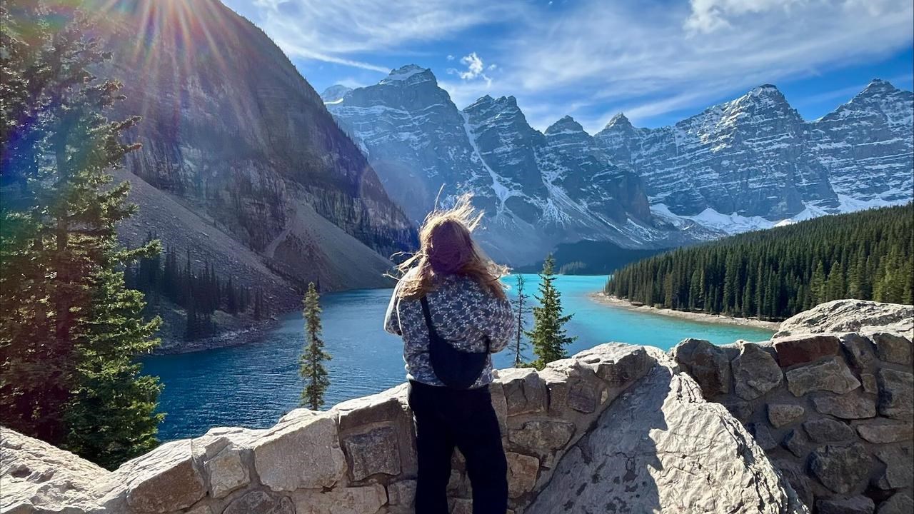 En kvinna står på en klippvägg med utsikt över en sjö.
