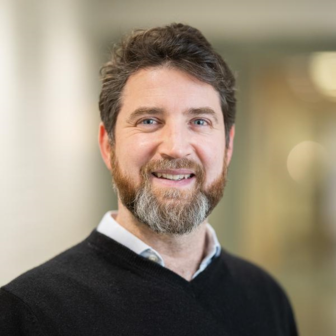 Researcher Olivier Keech smiles towards the camera. He is in focus, the background is blurry.