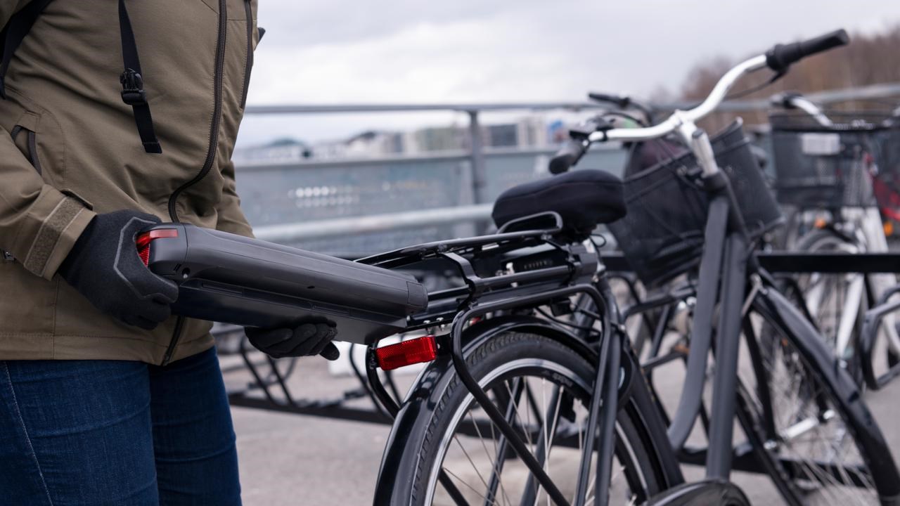 Person som sätter in ett batteri i en elcykel
