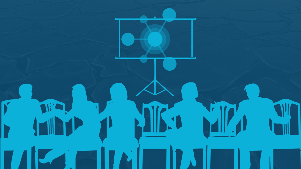 A group of people sitting at a table in front of a projector screen