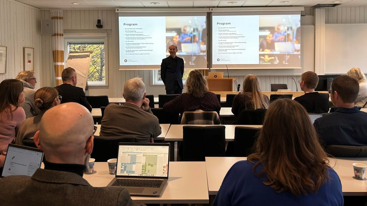 En grupp människor som sitter i ett mötesrum och lyssnar på en talare.