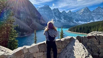 En kvinna står på en klippvägg med utsikt över en sjö.