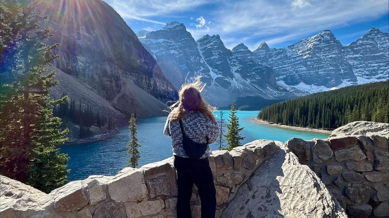 En kvinna står på en klippvägg med utsikt över en sjö.