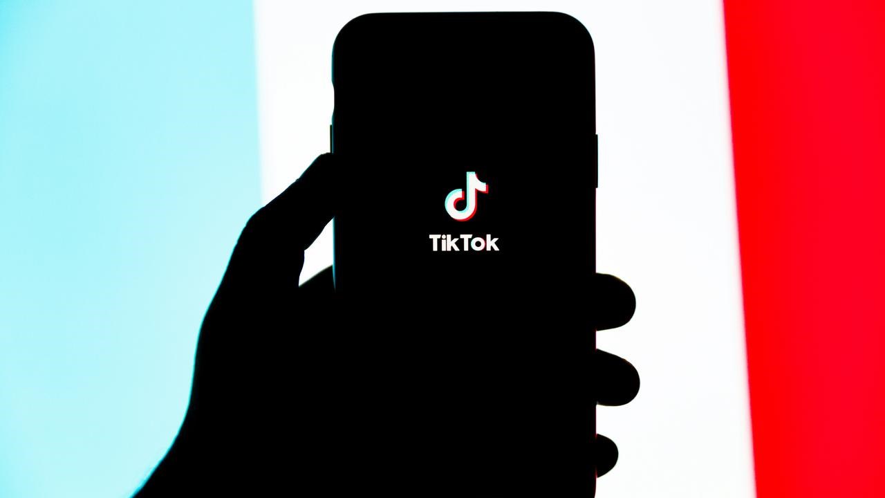 En person som håller en mobiltelefon i handen med Tiktok på.