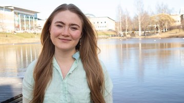 Porträttfoto på Johanna Birgersdotter, i bakgrunden dammen på campus.