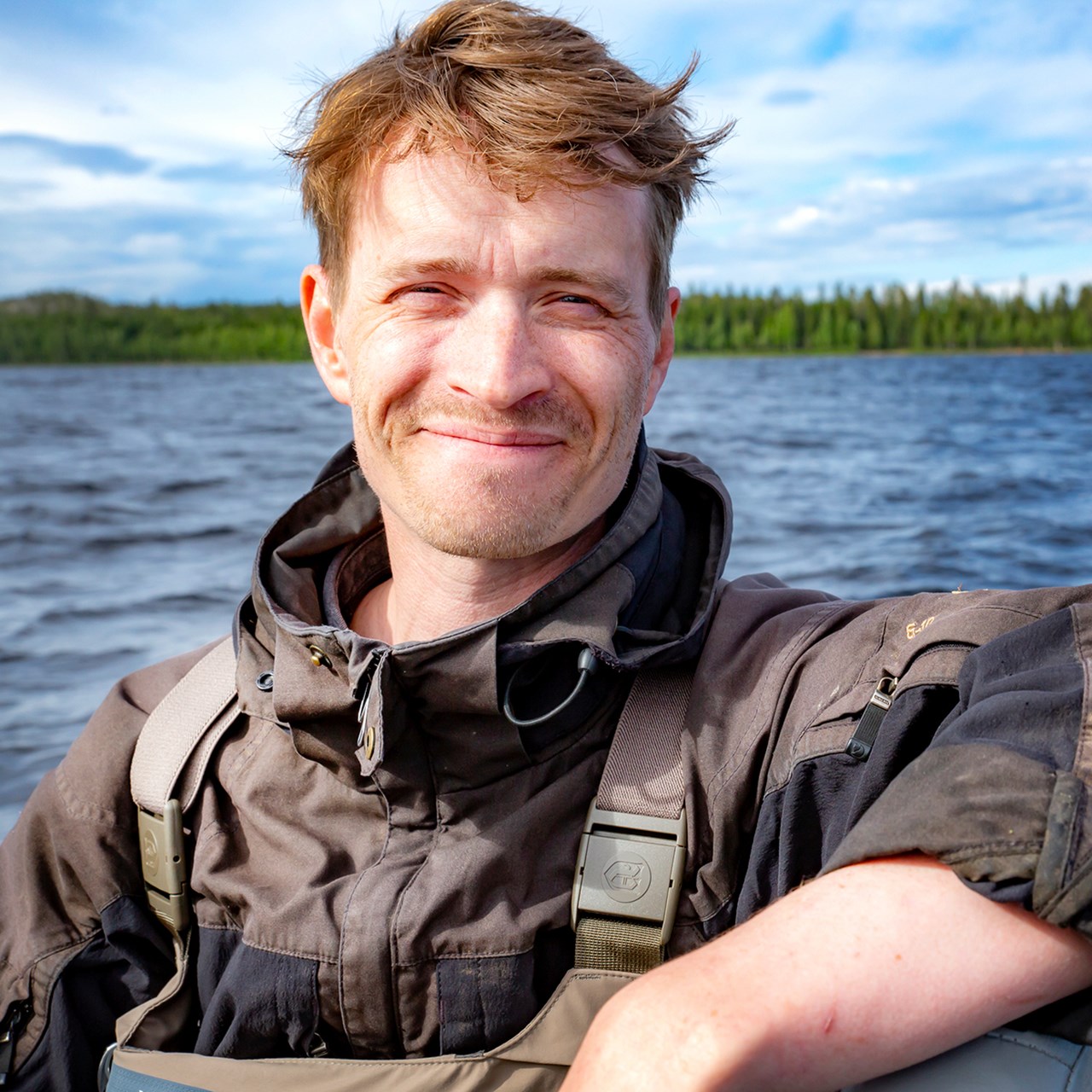 Man med fiskekläder och vatten i bakgrunden