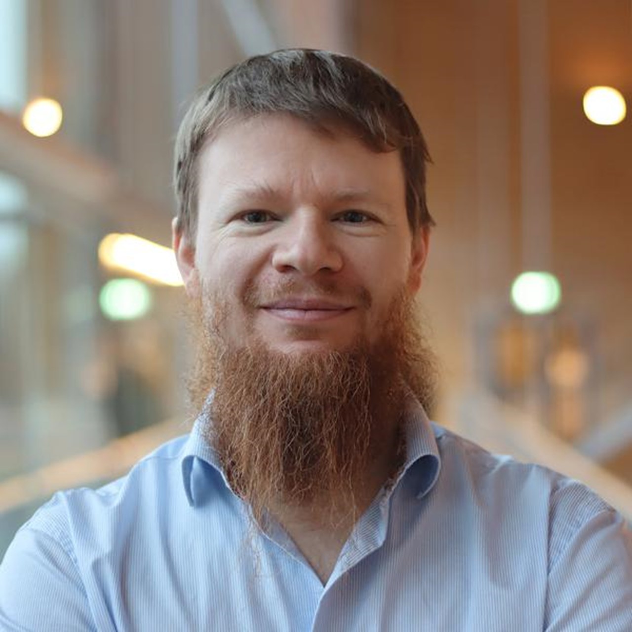Alexandre Bartel i kort h&aring;r och sk&auml;gg, st&aring;r vid f&ouml;nstret i ljusbl&aring; skjorta