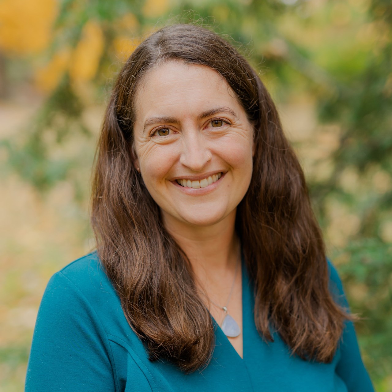 En kvinna med långt brunt hår som ler mot kameran.