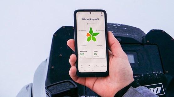 Person ute i vinterlandskap håller upp mobiltelefon med appen Star-C
