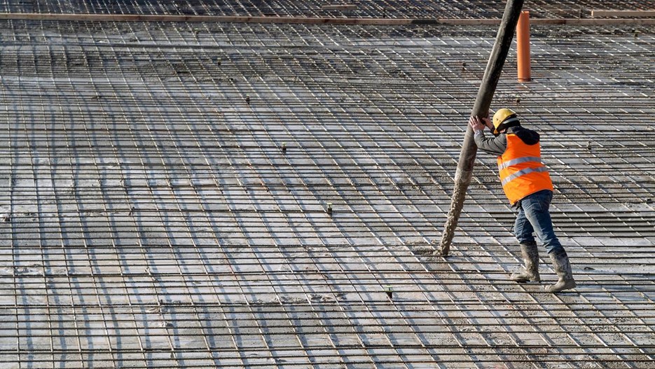 Person pumpar betong på en stor armerad konstruktion. 