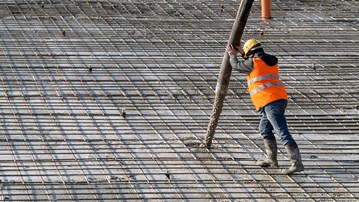 Person pumpar betong på en stor armerad konstruktion.