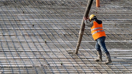 Person pumpar betong på en stor armerad konstruktion.
