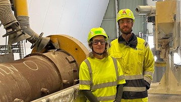 Två personer i varselkläder vid en cementugn.