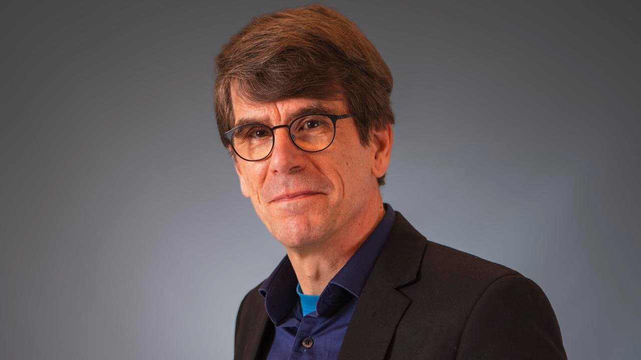 Mörkhårig man med glasögon tittar in i kameran.