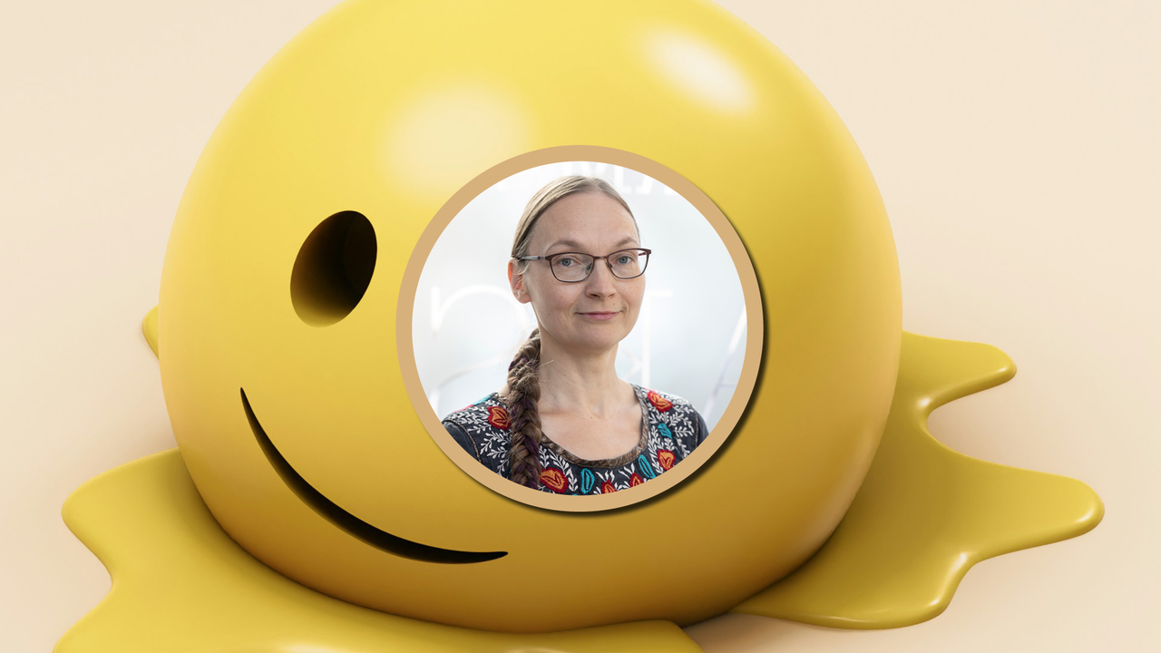 En kvinna med glasögon och ett leende på läpparna.