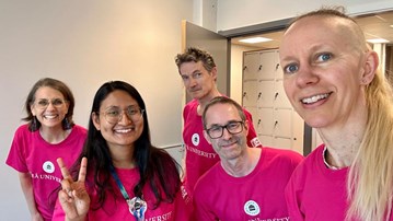 En grupp människor i rosa skjortor som poserar för en bild.