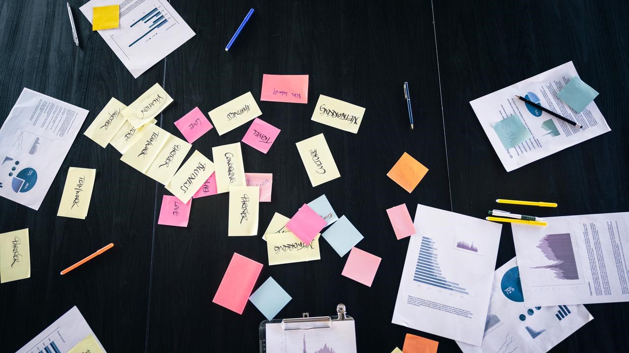 Dokument och post it-lappar ligger utspridda på ett bord.
