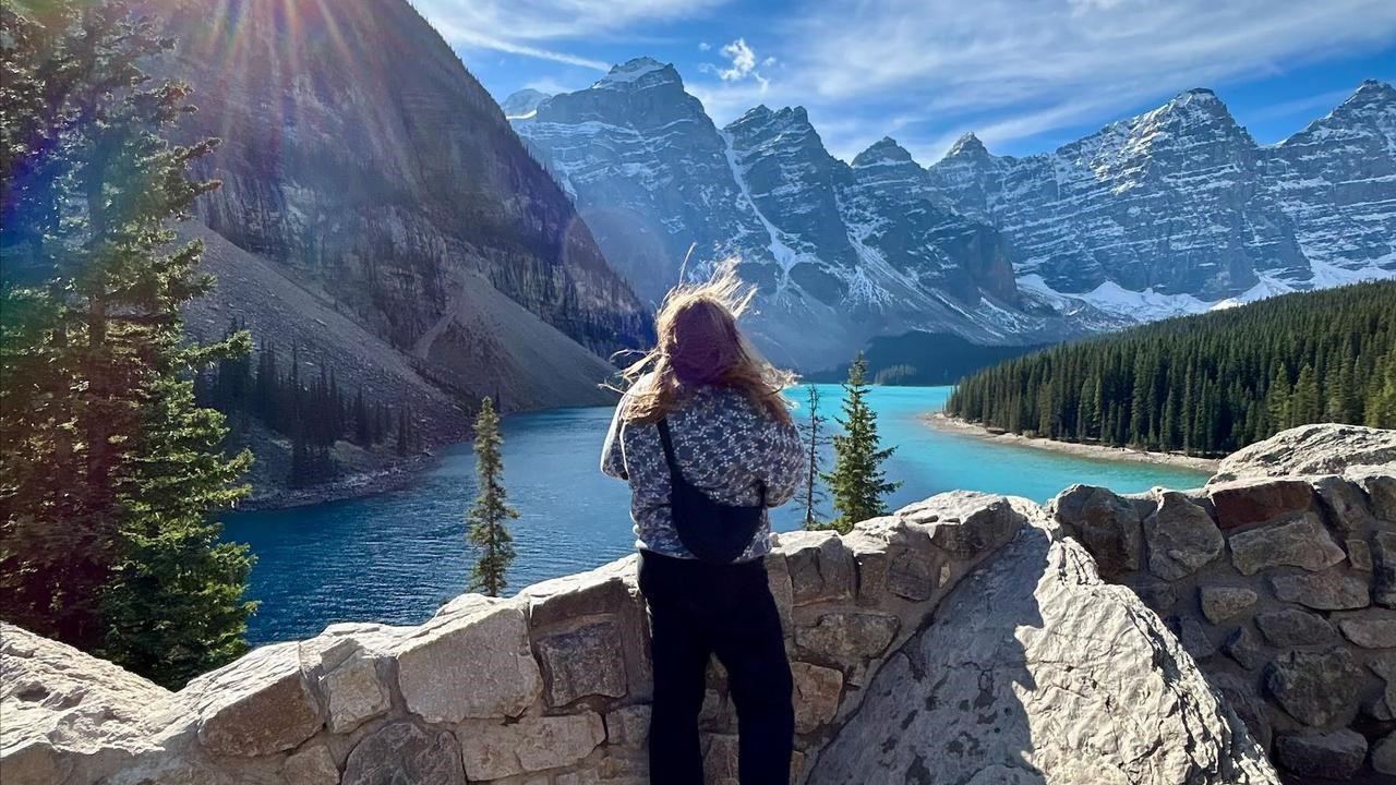 En kvinna står på en klippvägg med utsikt över en sjö.