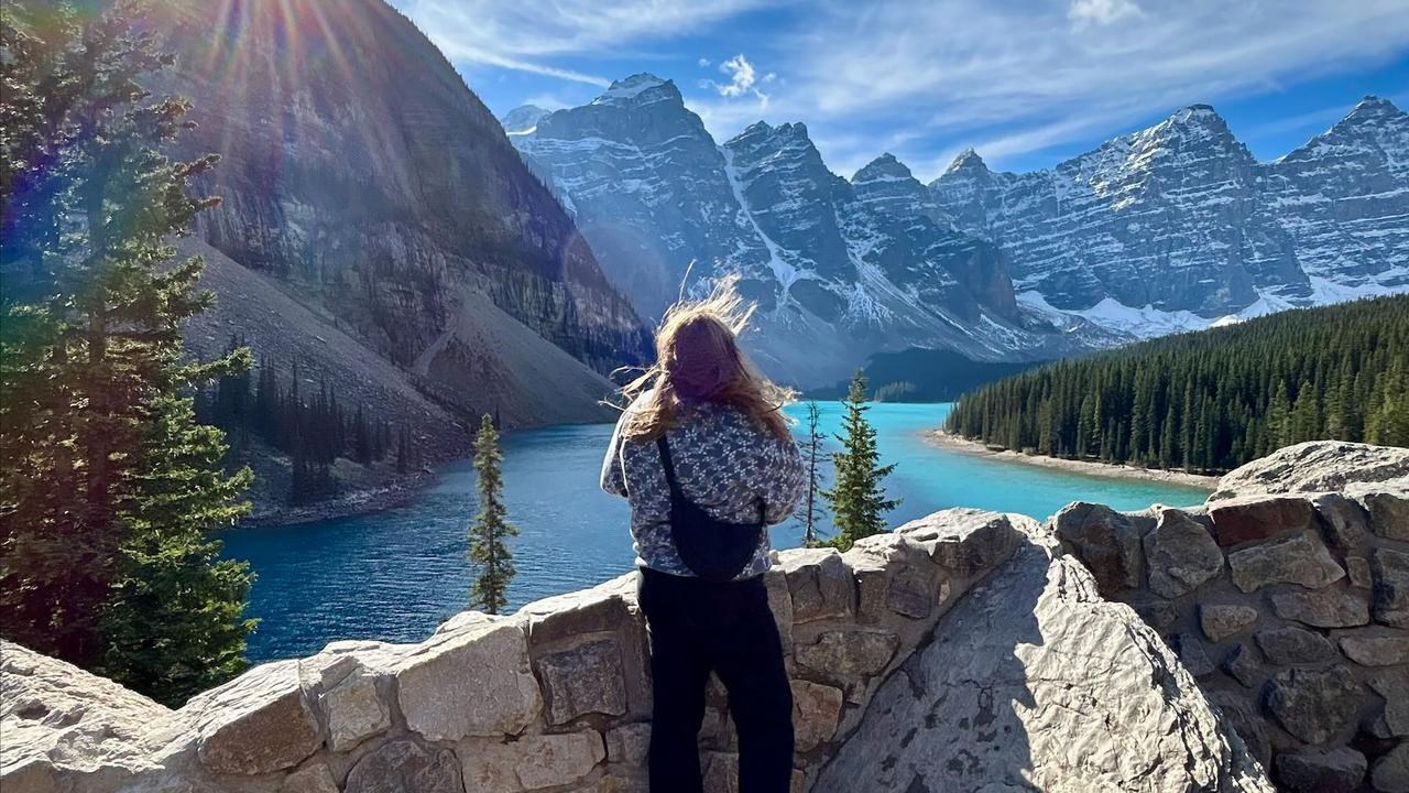 En kvinna står på en klippvägg med utsikt över en sjö.