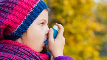 Astmasjukt barn inhalerar astmamedicin.
