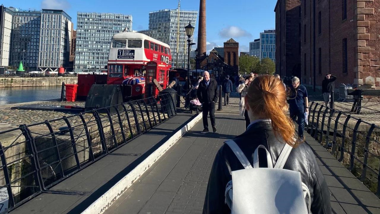 En kvinna med ryggsäck går över en bro.