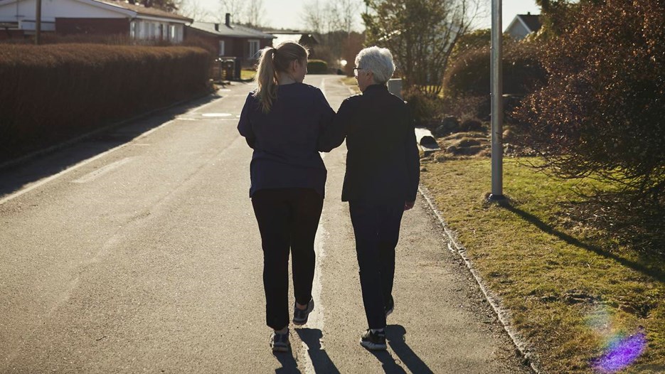 Äldre och yngre kvinna promenerar bort från fotografen