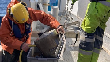 Forskare tar hand om bottenprov ombord på forskningsfartyg.