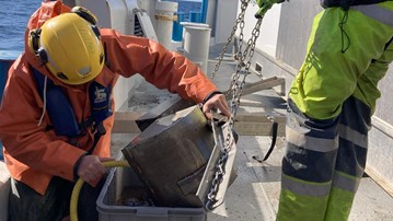 Researchers working with sediment sample onboard research vessel.