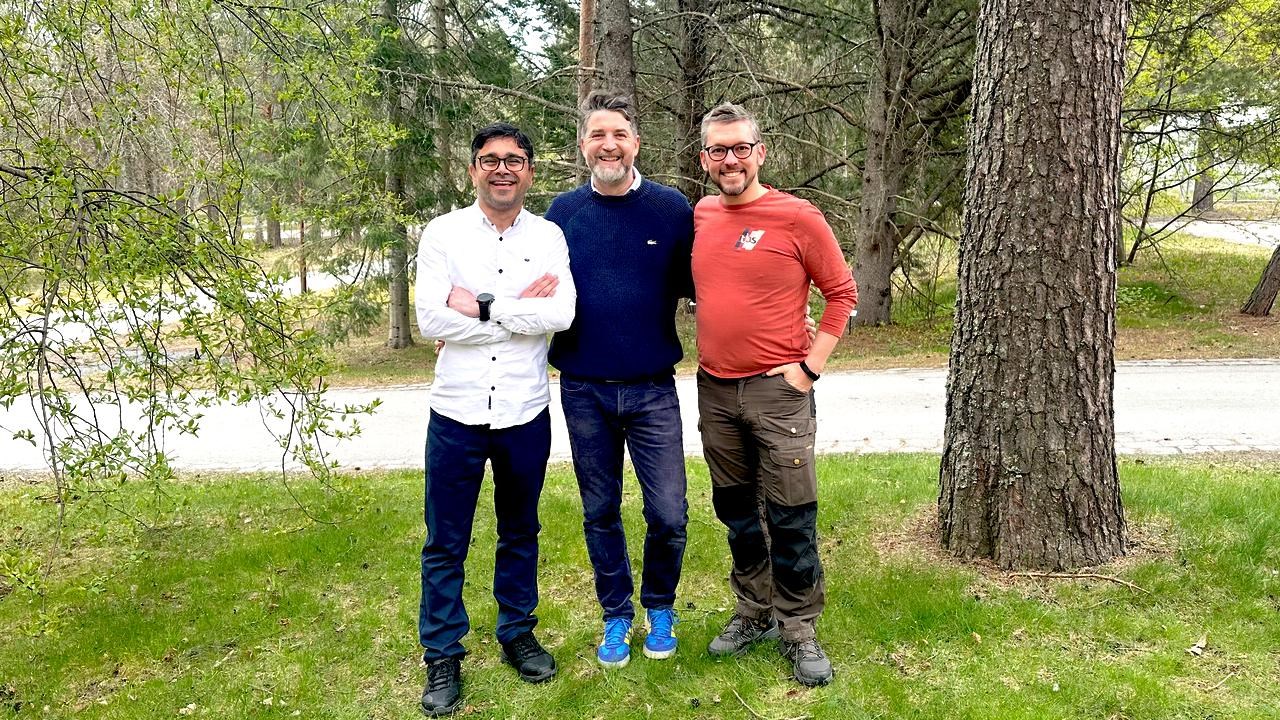 Three men are standing outdoors and posing for a group photograph./Tre m&auml;n st&aring;r utomhus och poserar f&ouml;r ett gruppfoto.