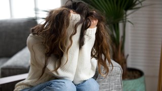 Kvinna som döljer sitt ansikte i sina händer. Ska illustrera psykisk ohälsa, depression, nedstämdhet eller liknande.
