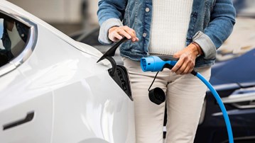 Bild på kvinna som sätter i kontakt för att ladda en elbil