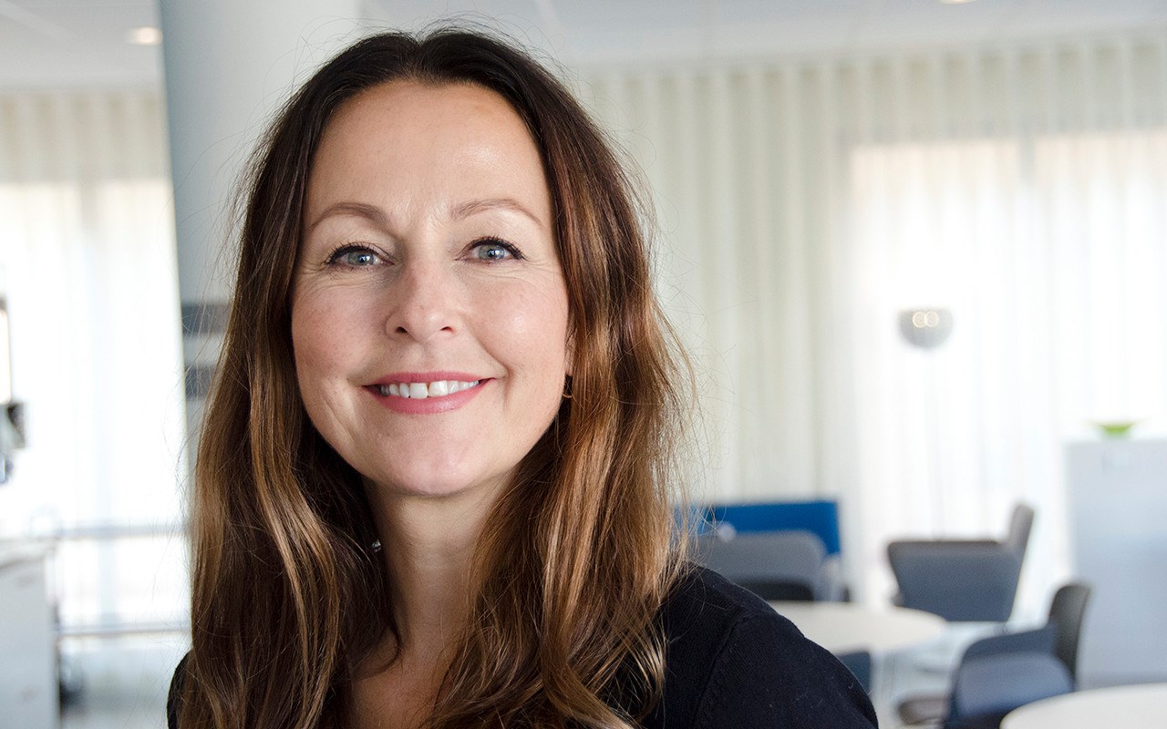 A woman with long brown hair smiling at the camera.