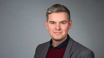 Porträtt av Emil Wistrand med grå bakgrund.