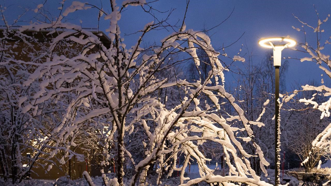 Vy över snötäckt Campus Umeå i skymningen i december.