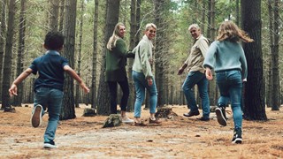 Familj med barn ute på promenad i barrskog.