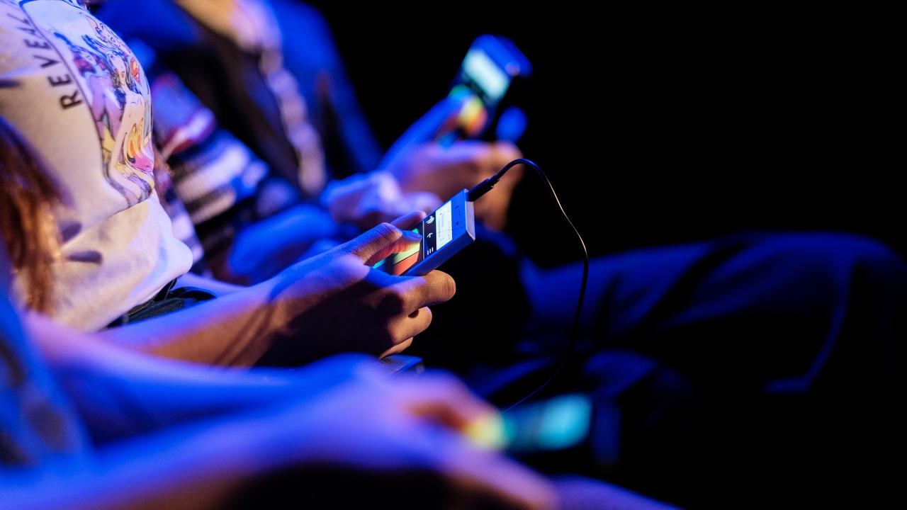 En grupp människor som sitter bredvid varandra och håller i mobiltelefoner.