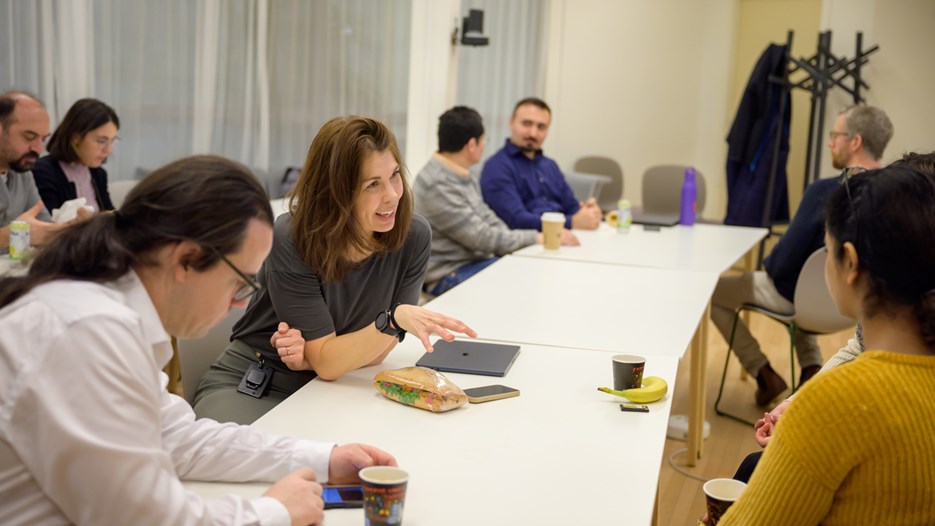 Elin Chorell sits at a white table and talks to two other researchers