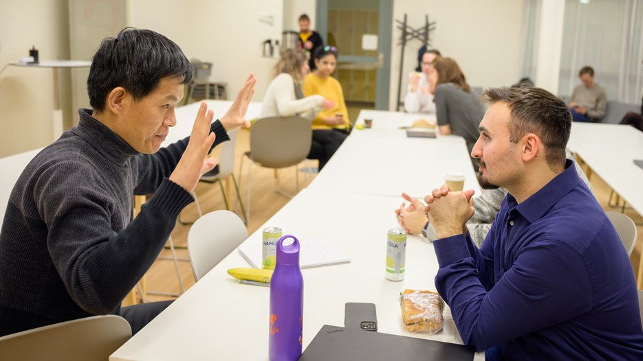 Jian-Feng Mao and Cemal Erdem sit across from each other at a white table and discuss.