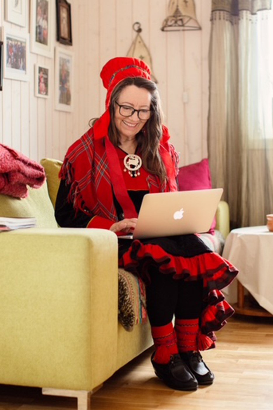 En kvinna sitter i en soffa och använder en bärbar dator.