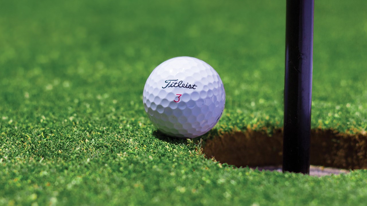 Golfboll vid hål på en green.